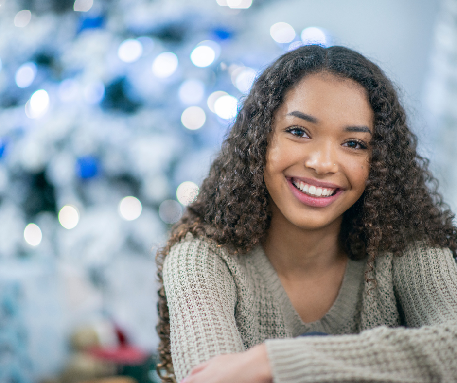 Teen girl with Christmas tree in background