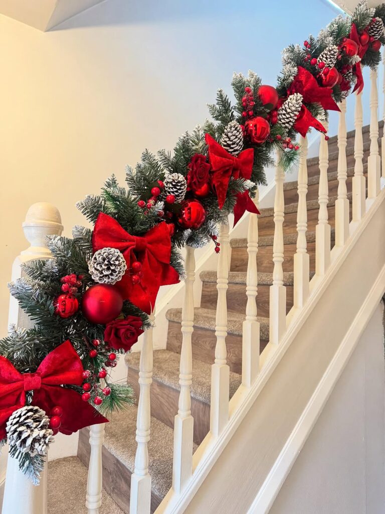 Staircase decorated with garland, bows and berries